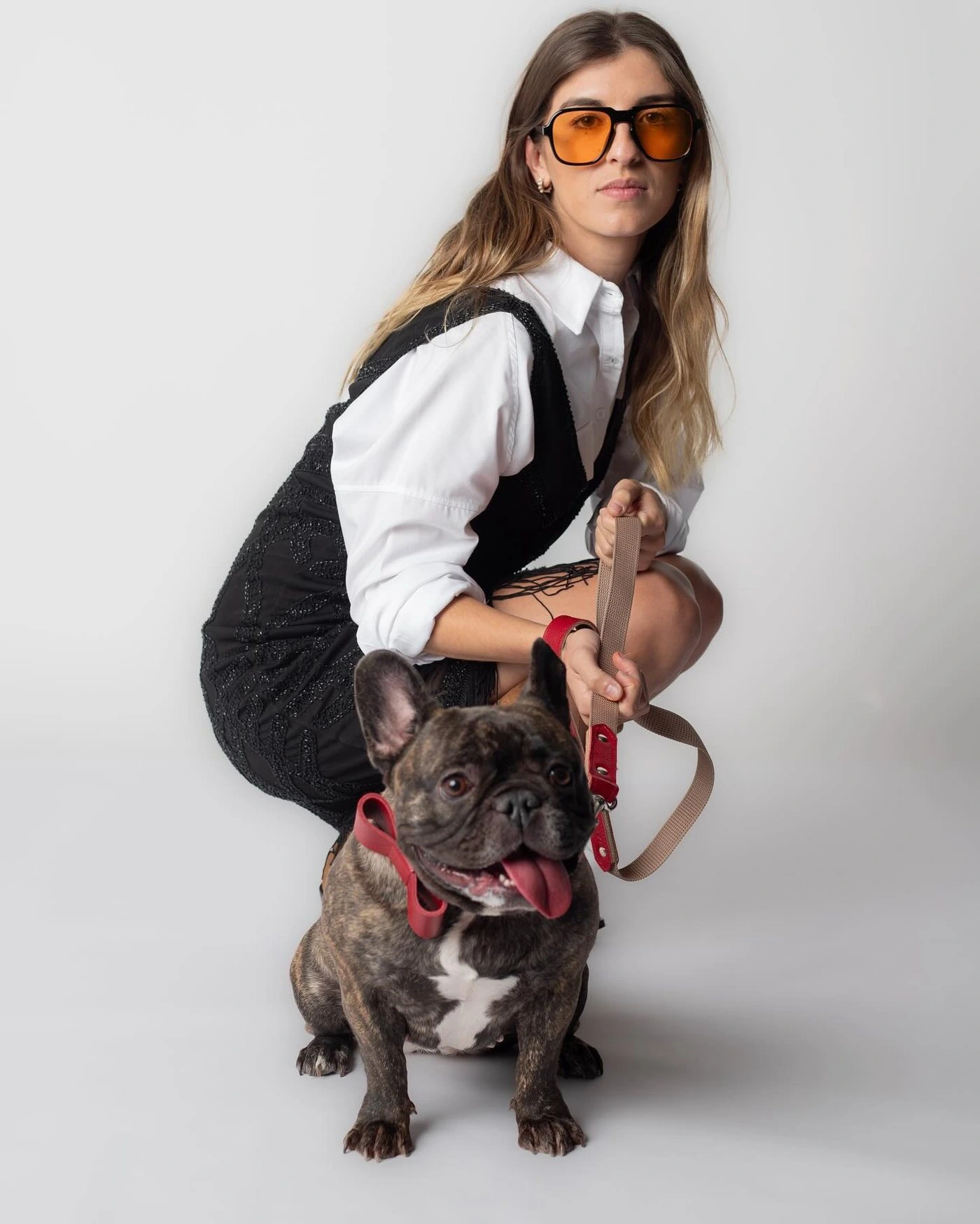 Modelo con gafas naranjas posando junto a un bulldog francés